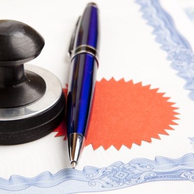 Apostille und Legalisation Blauschreiber und Siegel auf einem Dokument mit rotem Abzeichen.